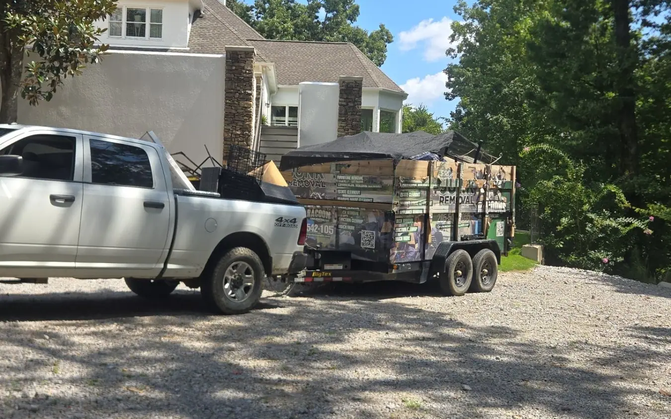 Racoons Junk Removal pickup and tarped dump trailer in a gravel driveway near Birmingham, AL